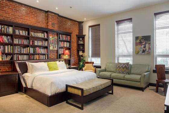 open space of study suite with king bed, green couch and bench, 