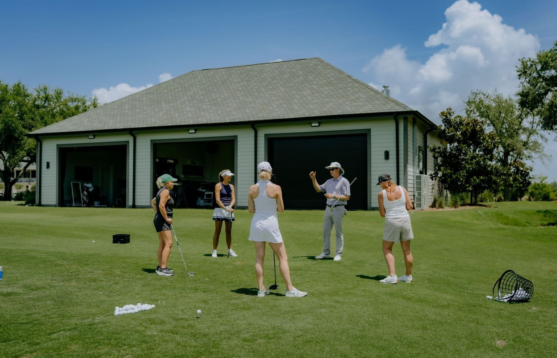 Group of golfers with instructor on green with club house behind them at Camp Creek Inn