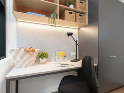 A neat study area with a desk, chair, large cabinet, and open shelving above.