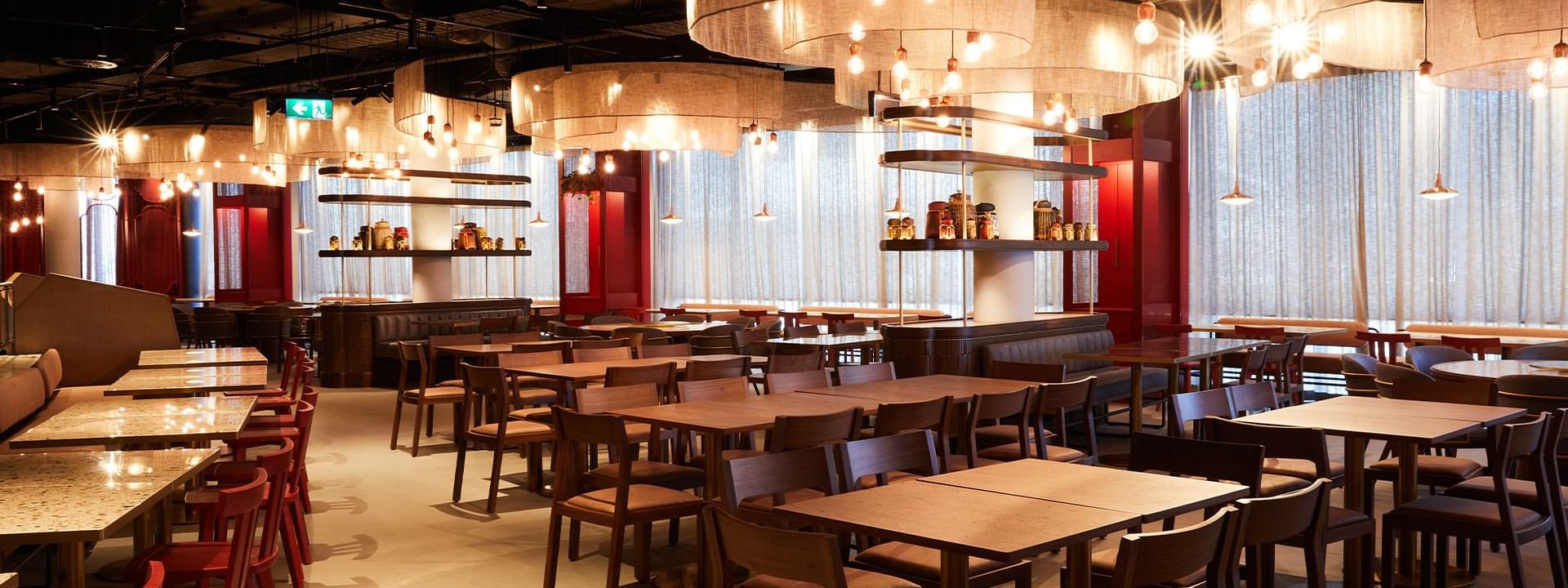 Spacious, elegantly lit New Town Thai Restaurant interior with numerous wooden tables and chairs at Novotel Sydney
