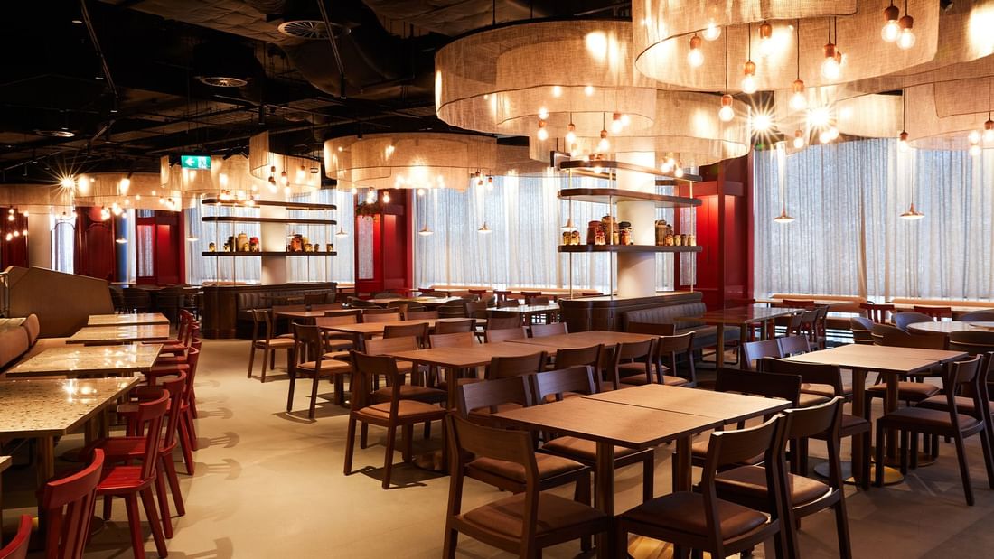 Spacious, elegantly lit New Town Thai Restaurant interior with numerous wooden tables and chairs at Novotel Sydney