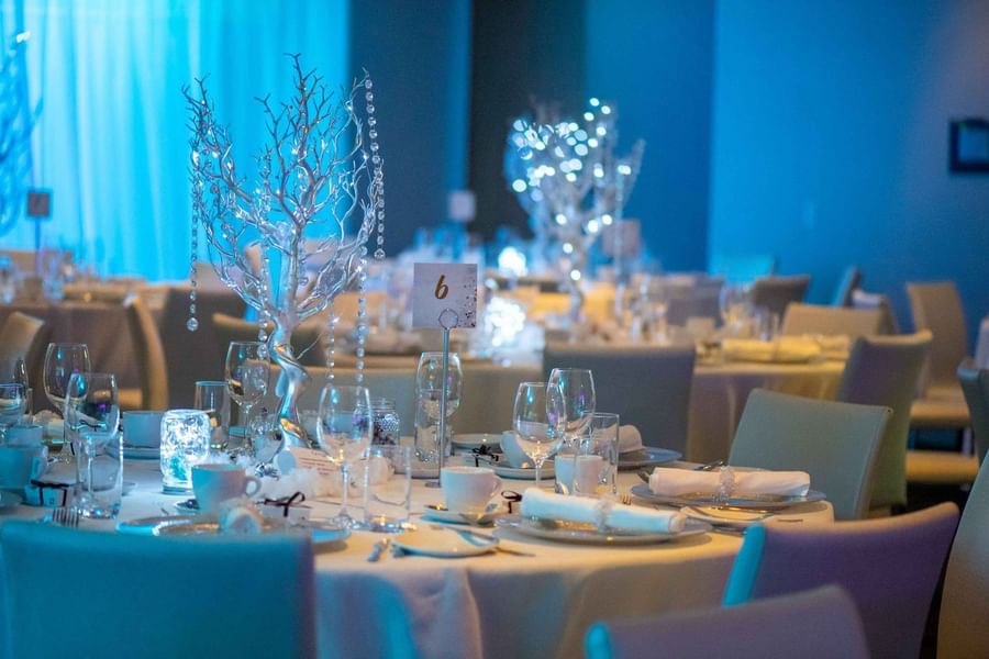 Elegant dining tables with glasses & plates and silver tree centerpieces at Warwick Le Crystal Montréal