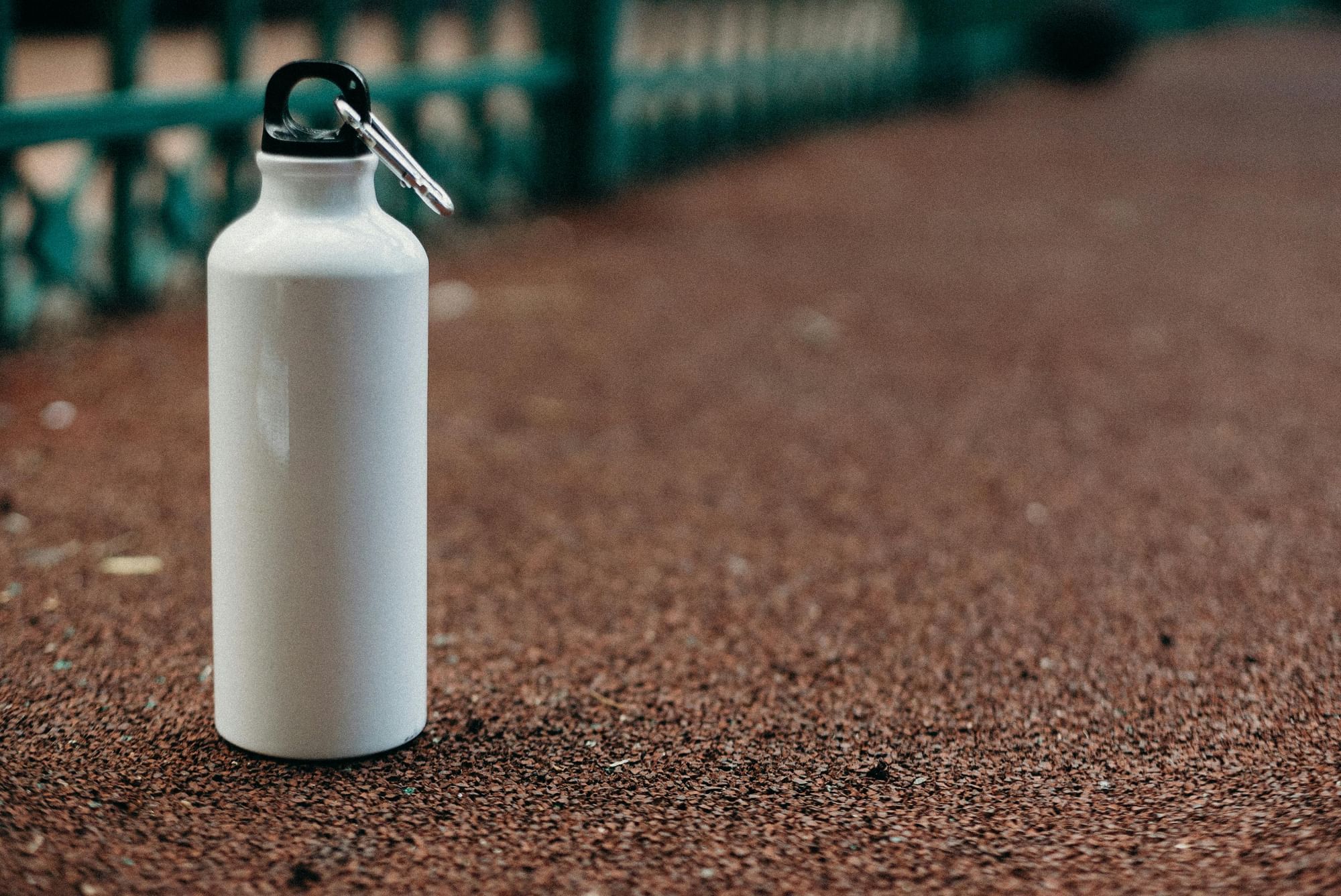 A white reusable water bottle on a paved path. 