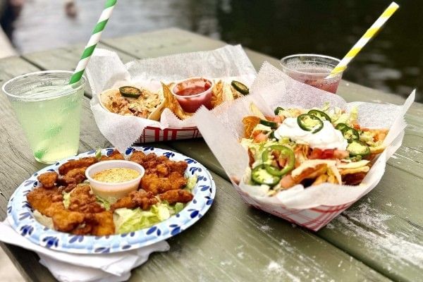 A table of fried gator nuggets, nachos, tacos, and cocktails from Without a Paddle Cafe at Wekiva Island.