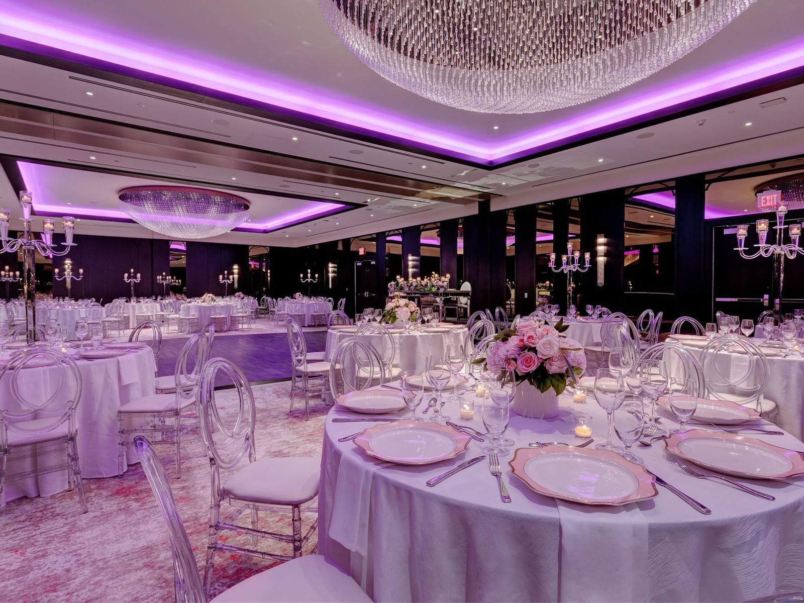 Elegant hall with purple lighting, crystal chandeliers, and decorated tables in Princes' Gates Ballroom at Hotel X Toronto