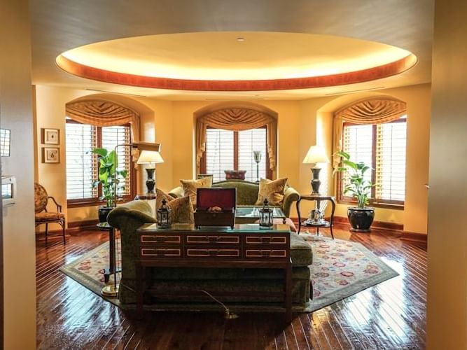 Grand King Suite living room with elegant sofas, rich wood floors, and natural light from bay windows at The Rose Hotel