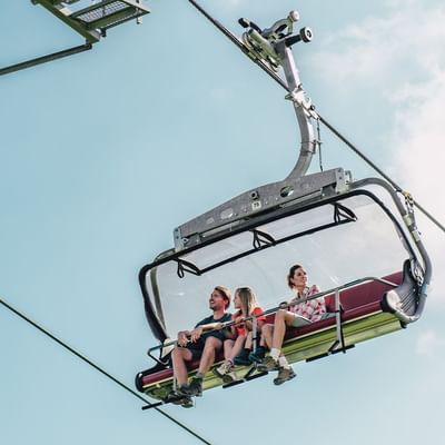 A family enjoying a chairlift ride near Falkensteiner Hotels