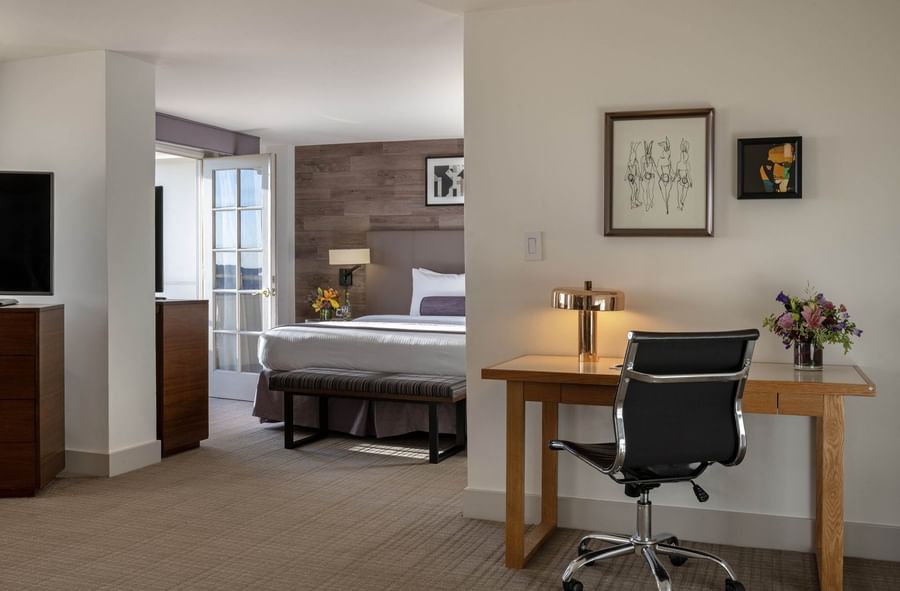 Office desk and chair by a gold lamp near a view into a bedroom suite area in Executive suite  at Warwick Denver