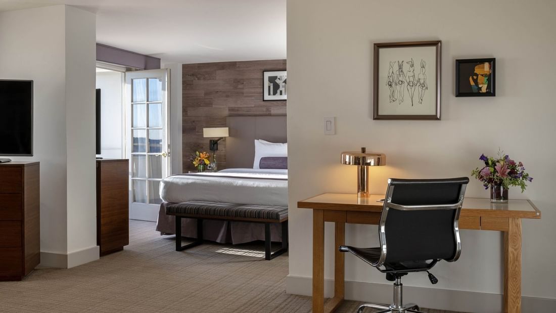 Office desk and chair by a gold lamp near a view into a bedroom suite area in Executive suite  at Warwick Denver