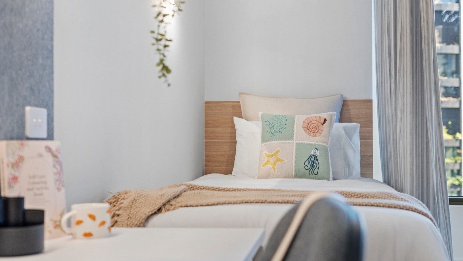 Cozy bedroom with marine-themed pillows and a decorative wall at UniLodge Brisbane City.