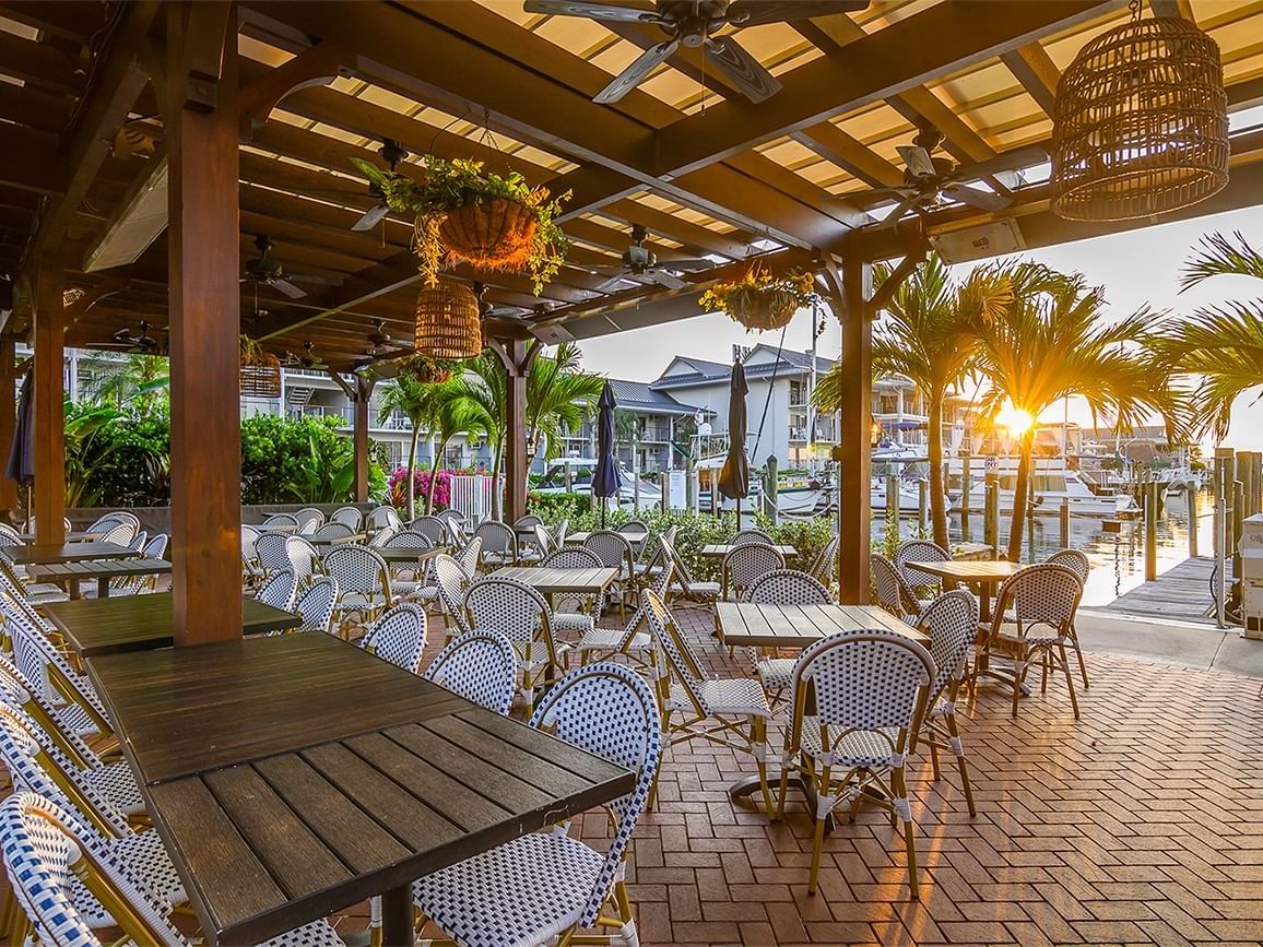 Outdoor restaurant area with wooden tables and chairs at The Dock at Crayton Cove in Naples.
