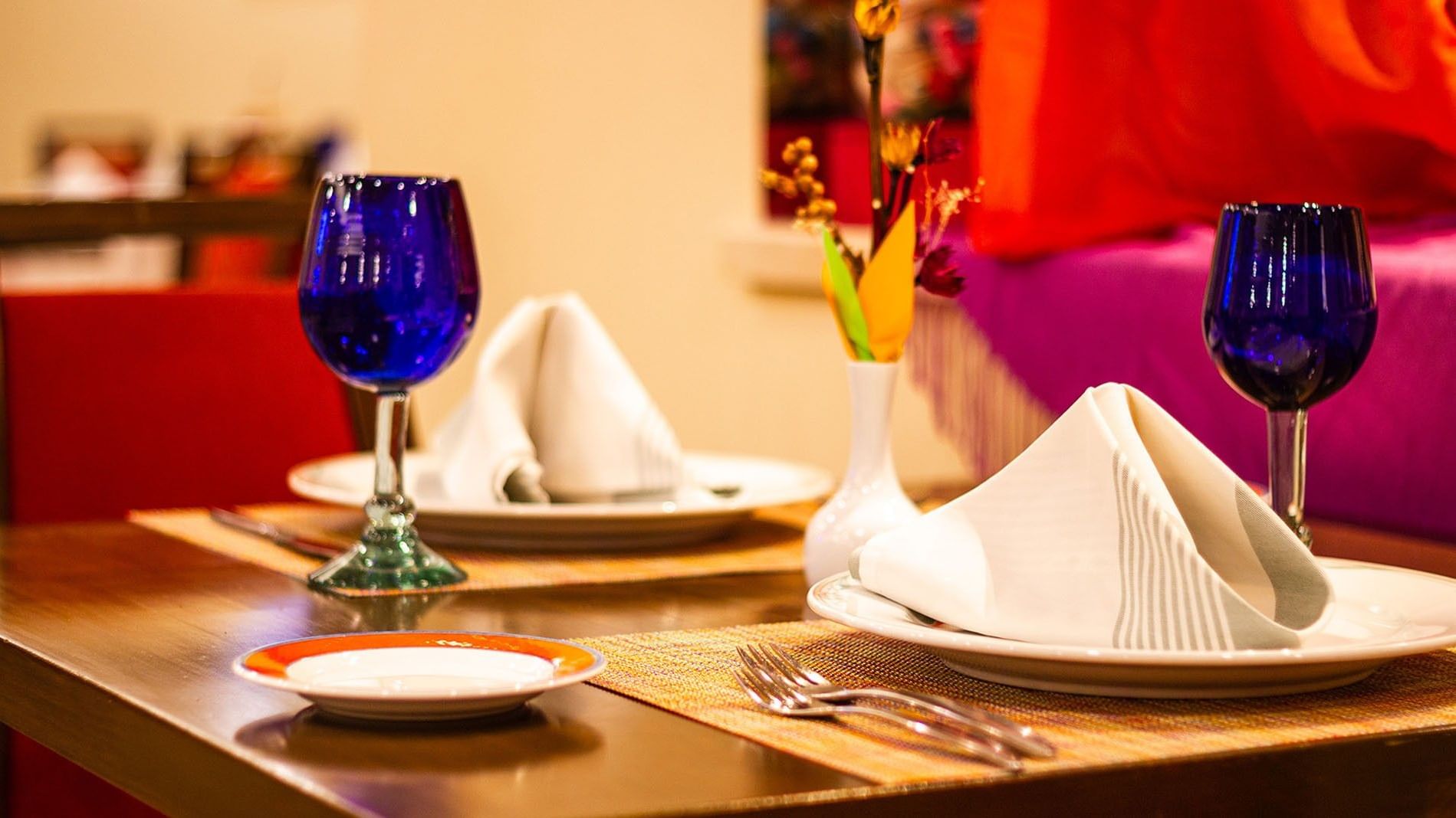 Two set tables with blue wine glasses and napkins at Cualli in Ciudad de Mexico at Camino Real Aeropuerto Mexico.