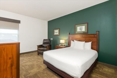 Queen bed, nightstand & cozy lounger in Single Queen ADA at Boothill Inn & Suites