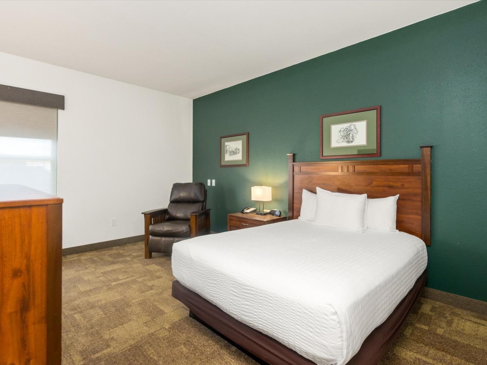 Queen bed, nightstand & cozy lounger in Single Queen ADA at Boothill Inn & Suites