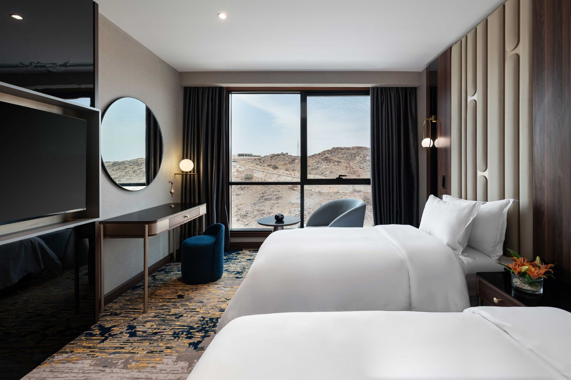 TV with work desk facing bed by the window in Deluxe Room at Warwick Al Taif Hotel