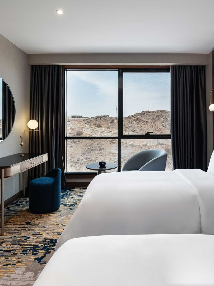 TV with work desk facing the bed by the window in Deluxe Room at Warwick Al Taif Hotel