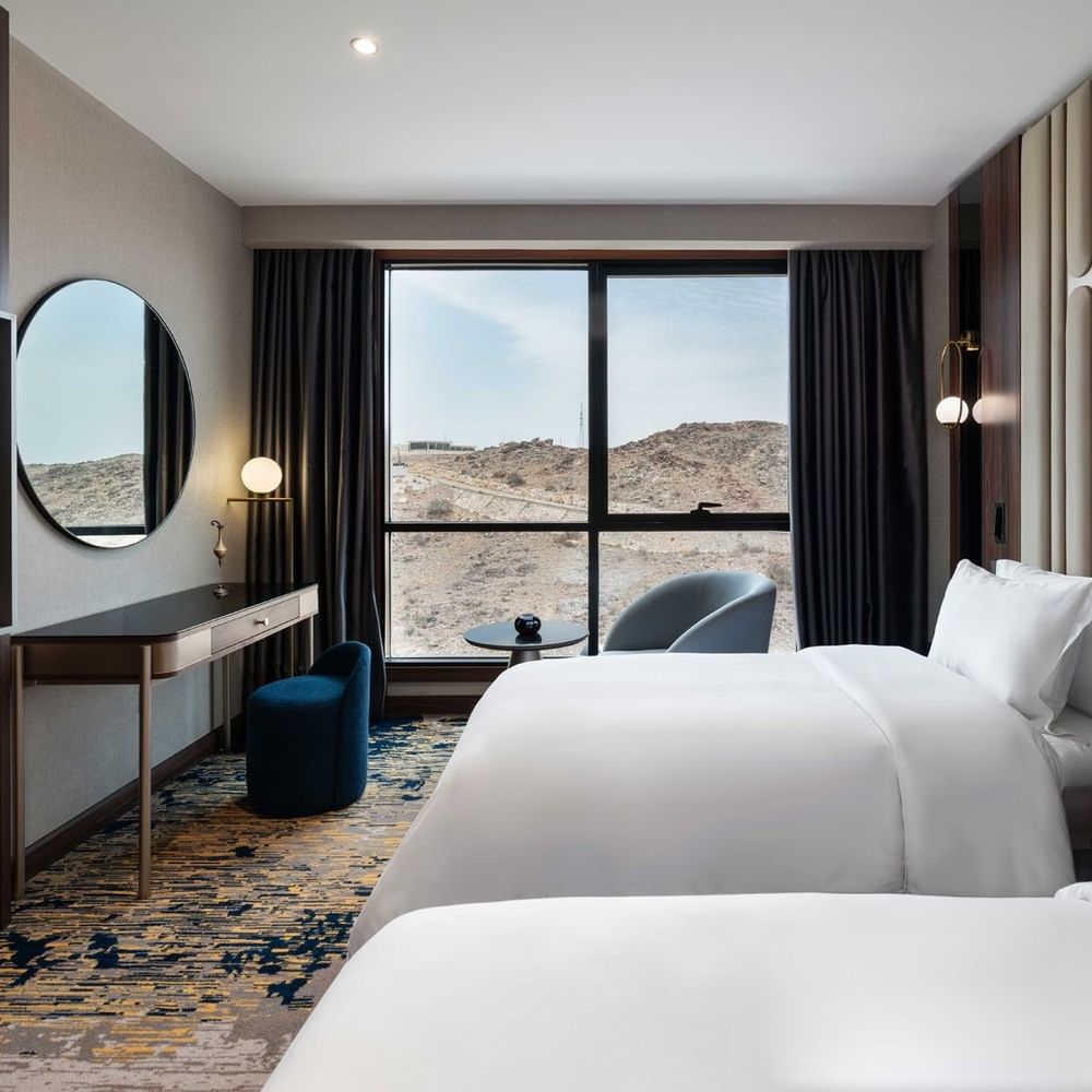 TV with work desk facing the bed by the window in Deluxe Room at Warwick Al Taif Hotel