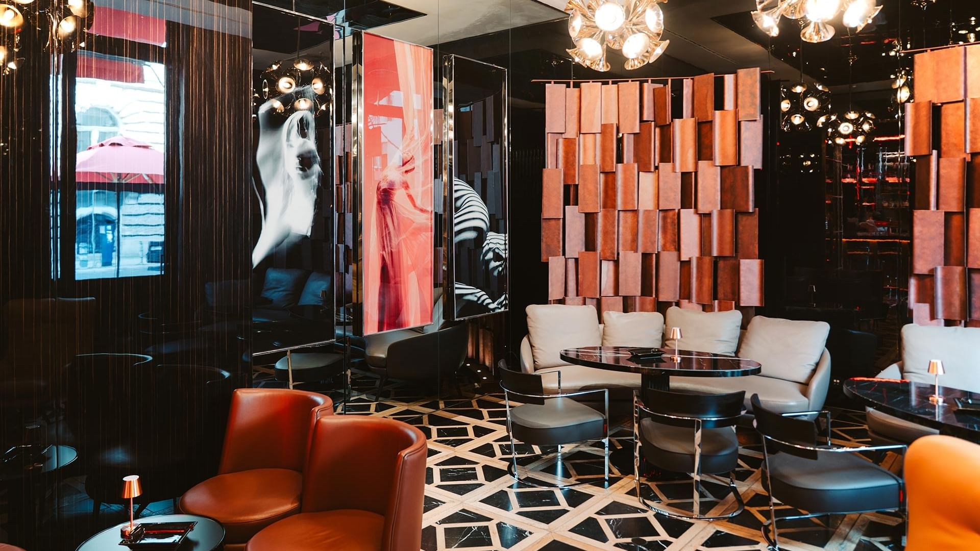 Stilvolle Lounge mit orangefarbenen Sesseln, geometrischem Boden und modernen Kronleuchtern im Titanic Gendarmenmarkt Berlin
