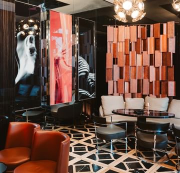 Stilvolle Lounge mit orangefarbenen Sesseln, geometrischem Boden und modernen Kronleuchtern im Titanic Gendarmenmarkt Berlin