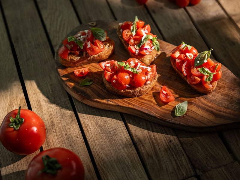 Baguette mit Tomaten und Basilikum auf Holzbrett