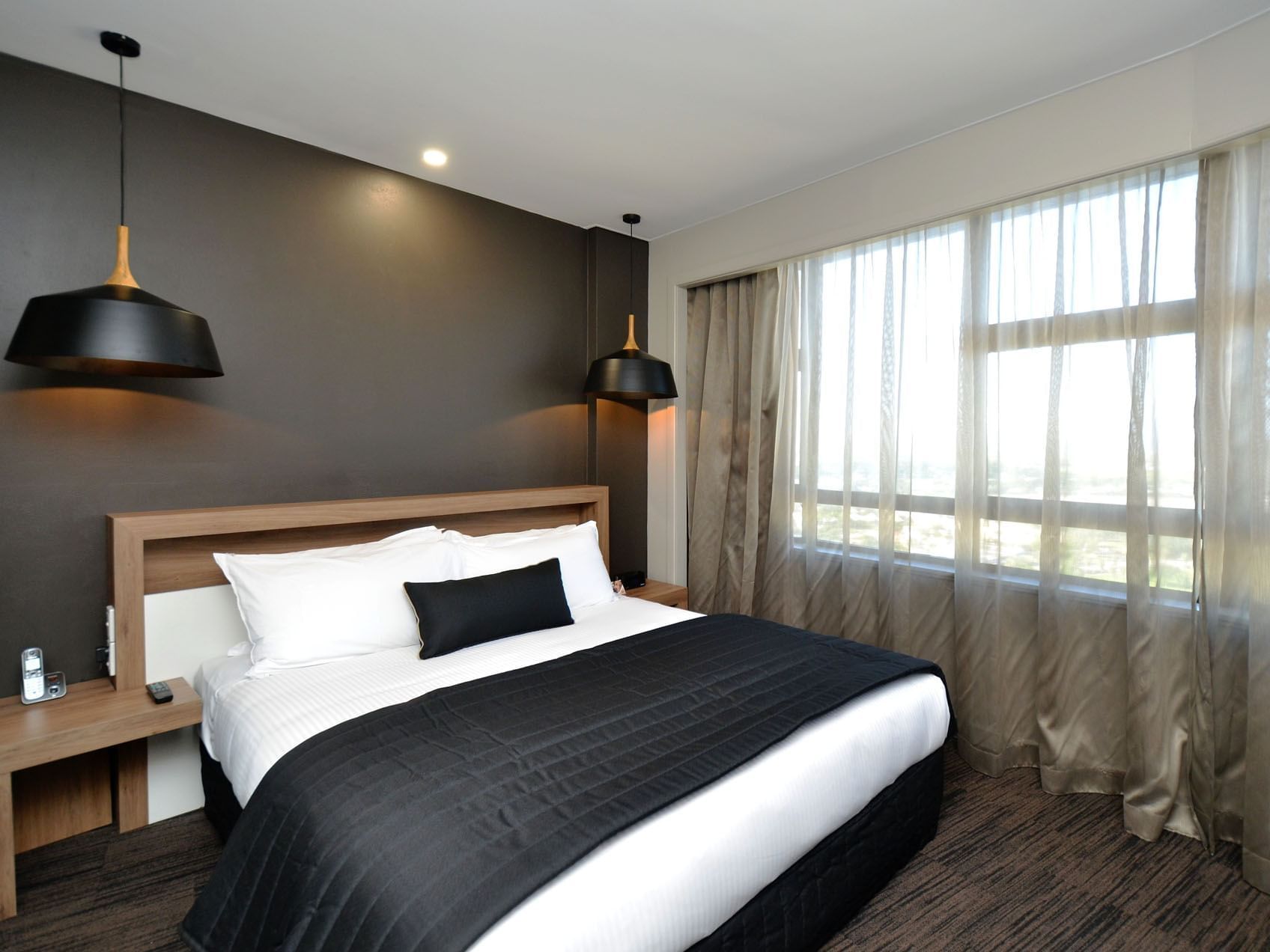 King bed with comfy pillows & hanging lamps in Executive Suite at Hotel Grand Chancellor Townsville