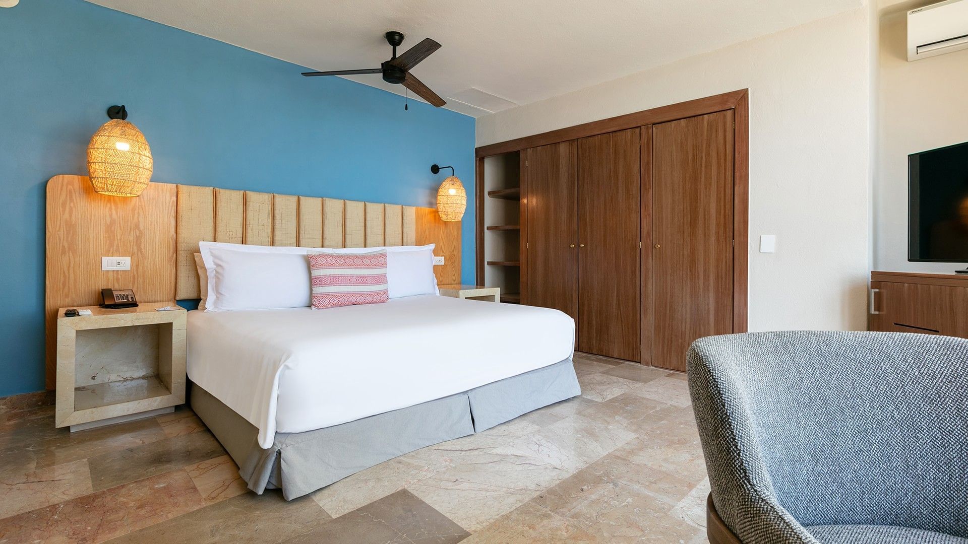 King Junior Suite with white linens and red patterned pillows under warm lamp at Camino Real Acapulco Diamante