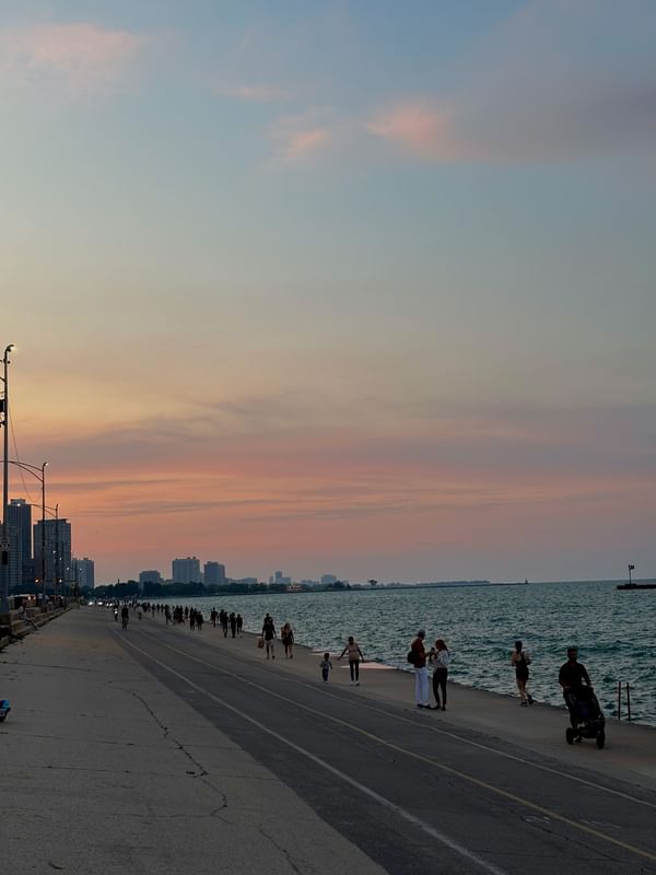 People walking along a waterfront under sunset sky at Warwick Allerton Chicago