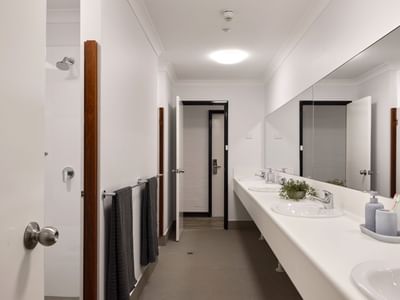 Clean communal bathroom with white sinks, towels, and mirrors at UniLodge Vickery House.