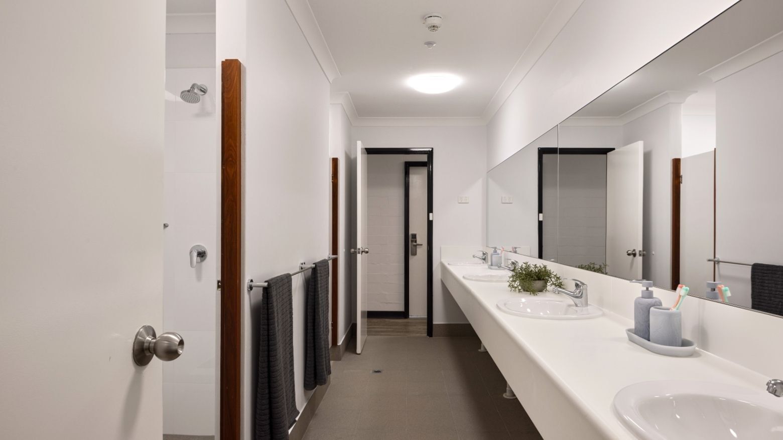Clean communal bathroom with white sinks, towels, and mirrors at UniLodge Vickery House.