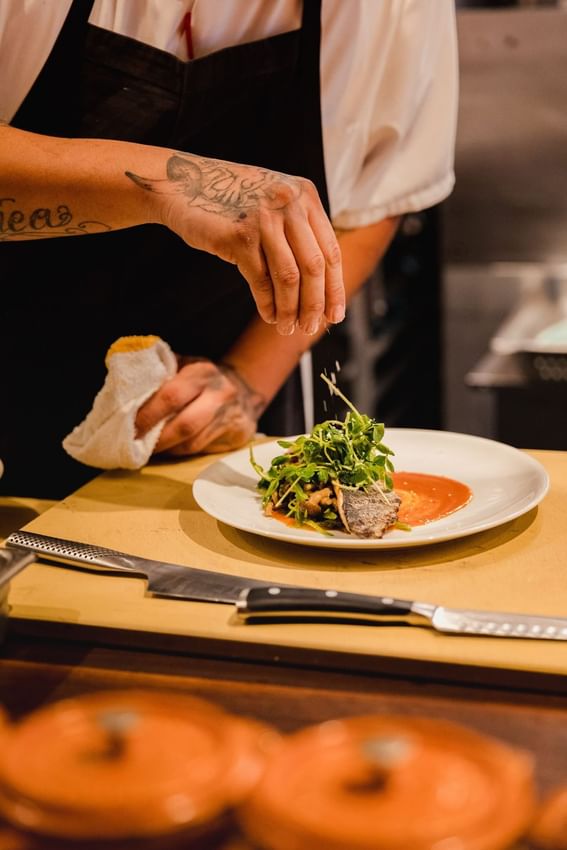 Close-up of a chef garnishing a meal in H Cafe and Bar at Alcyone Hotel Residences