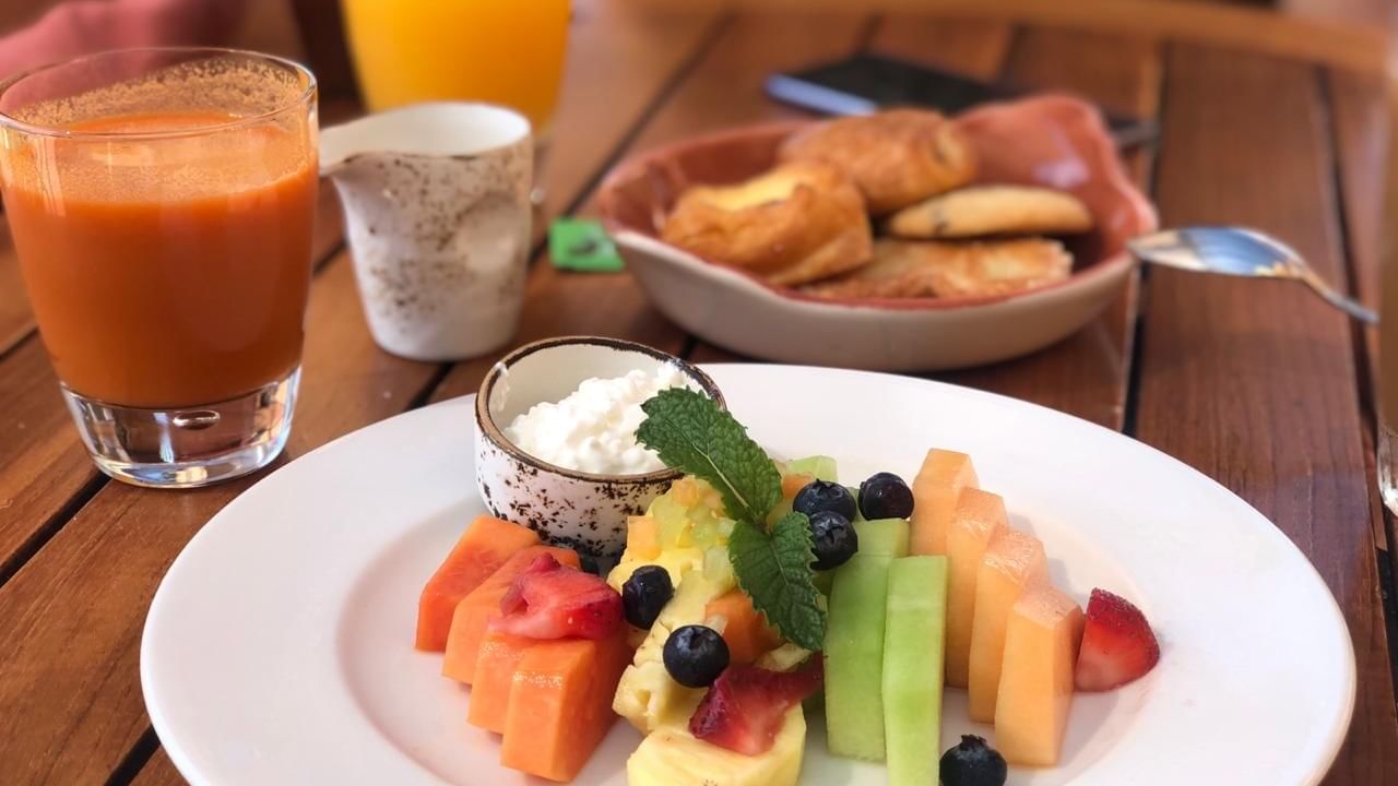 Fresh fruit, pastries, and orange juice served for breakfast on a wooden table at Tomates in Hacienda Del Mar Los Cabos.