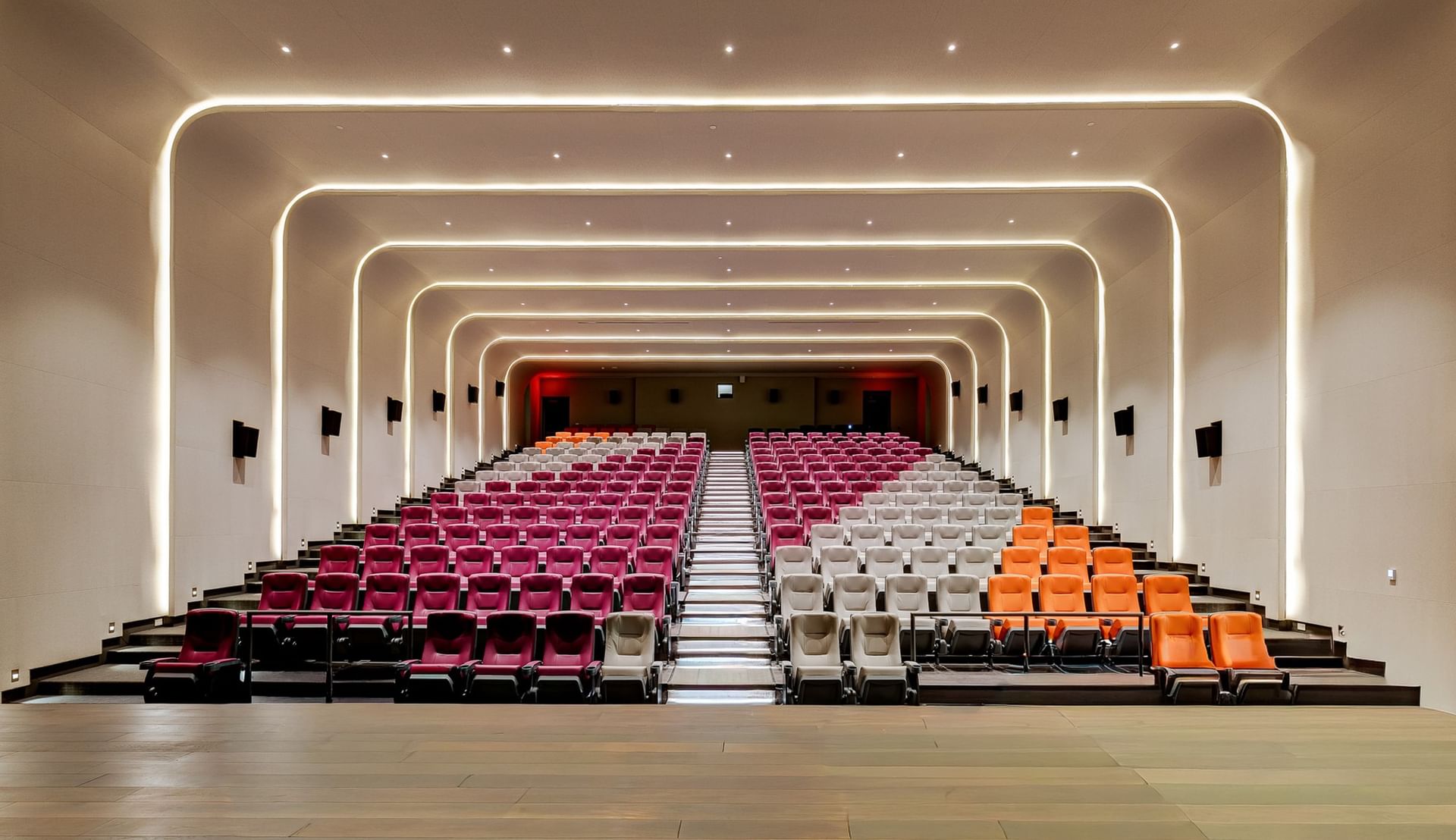 Cinema with colorful tiered seating, central staircase, and curved illuminated walls at Hotel X Toronto