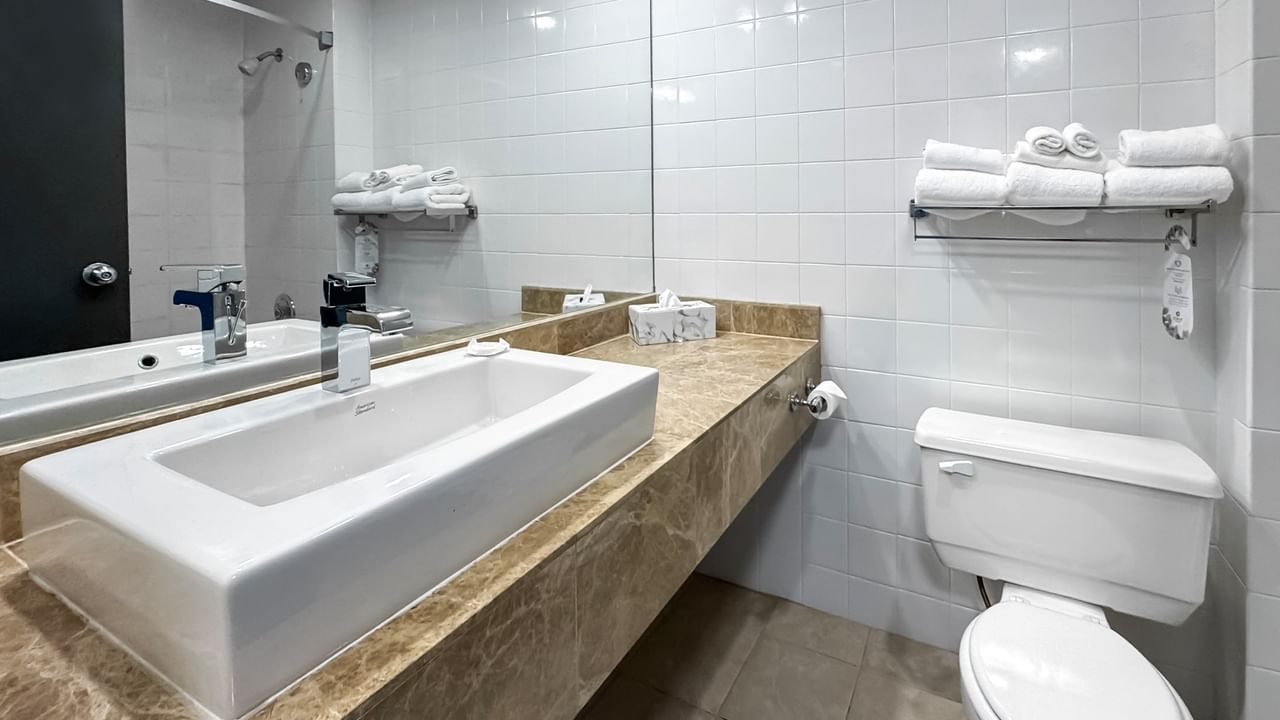 Coast Premium Two Queens bathroom with a sink, toilet, and white towels on a rack at Coast Lonsdale Quay Hotel