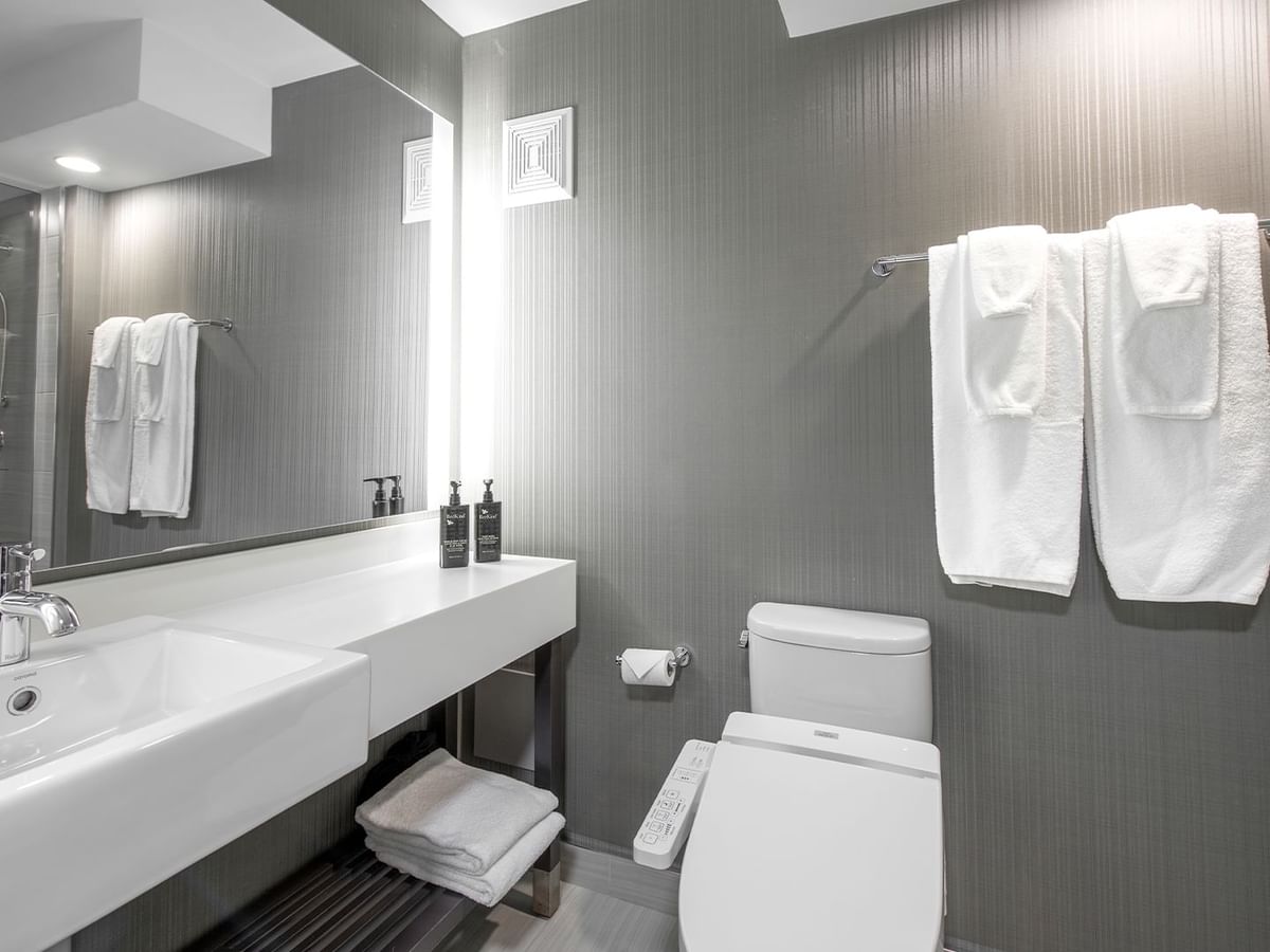 Bathroom with sink, toilet, towels, and a large mirror.