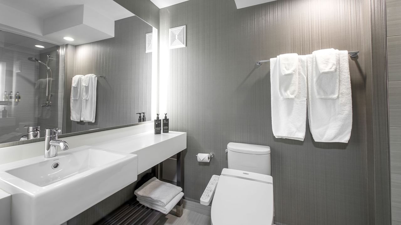 Bathroom with sink, toilet, towels, and a large mirror.