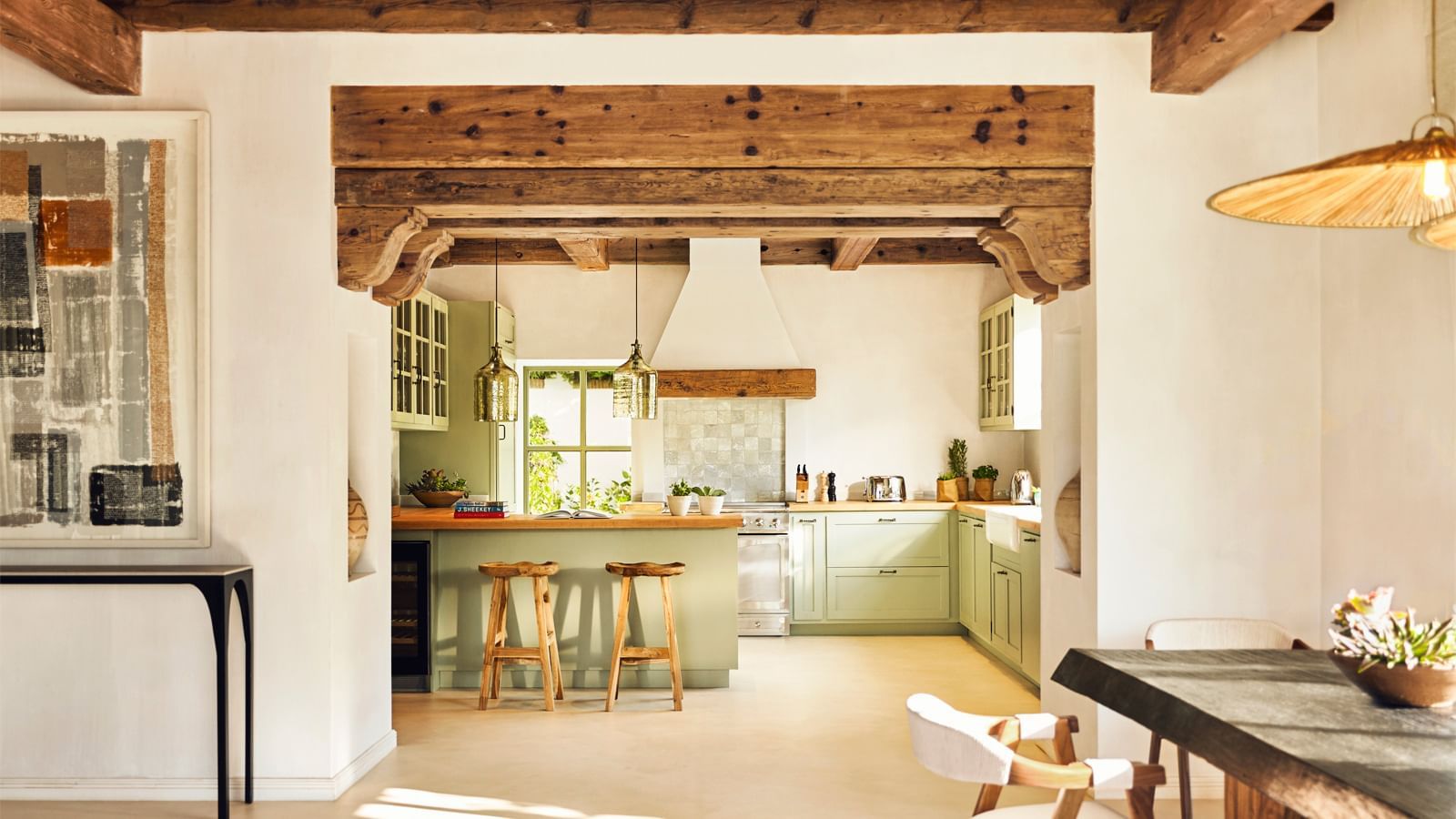 Pale green kitchen with a central island and bar stools placed under wooden beams at the Marbella Club