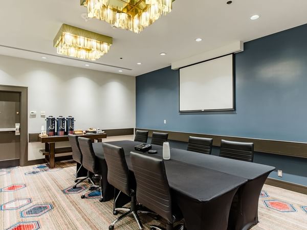 Meeting venue with tables, chairs, and a projector screen
