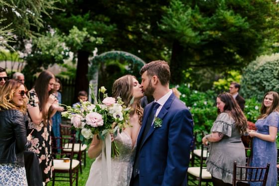 Bride and groom share a kiss during outdoor garden at Cambria Pines Lodge, an elite among wedding venues, Cambria, CA