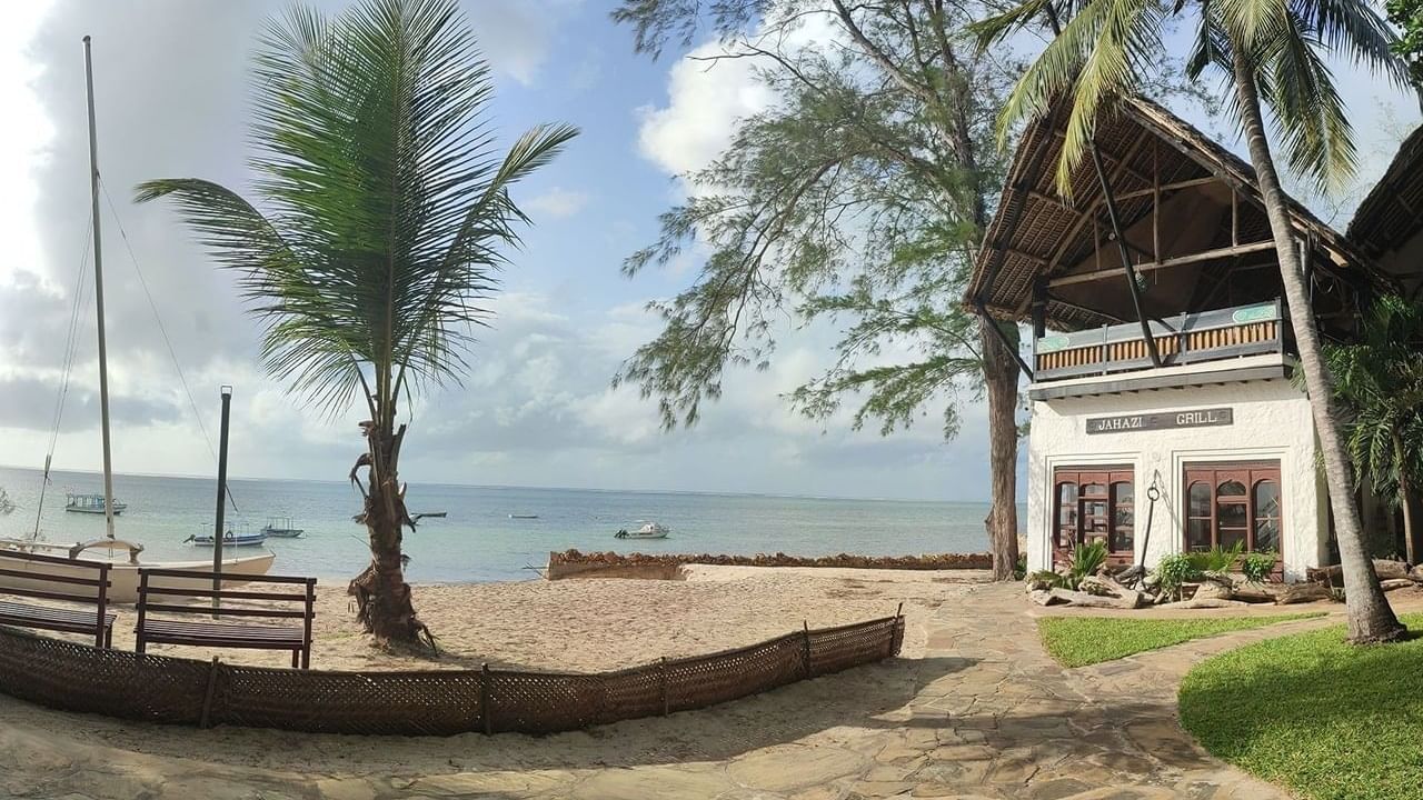 Beachfront grill by a tropical palm tree under a cloudy sky at Serena Hotels & Resorts, one of the best unique resorts