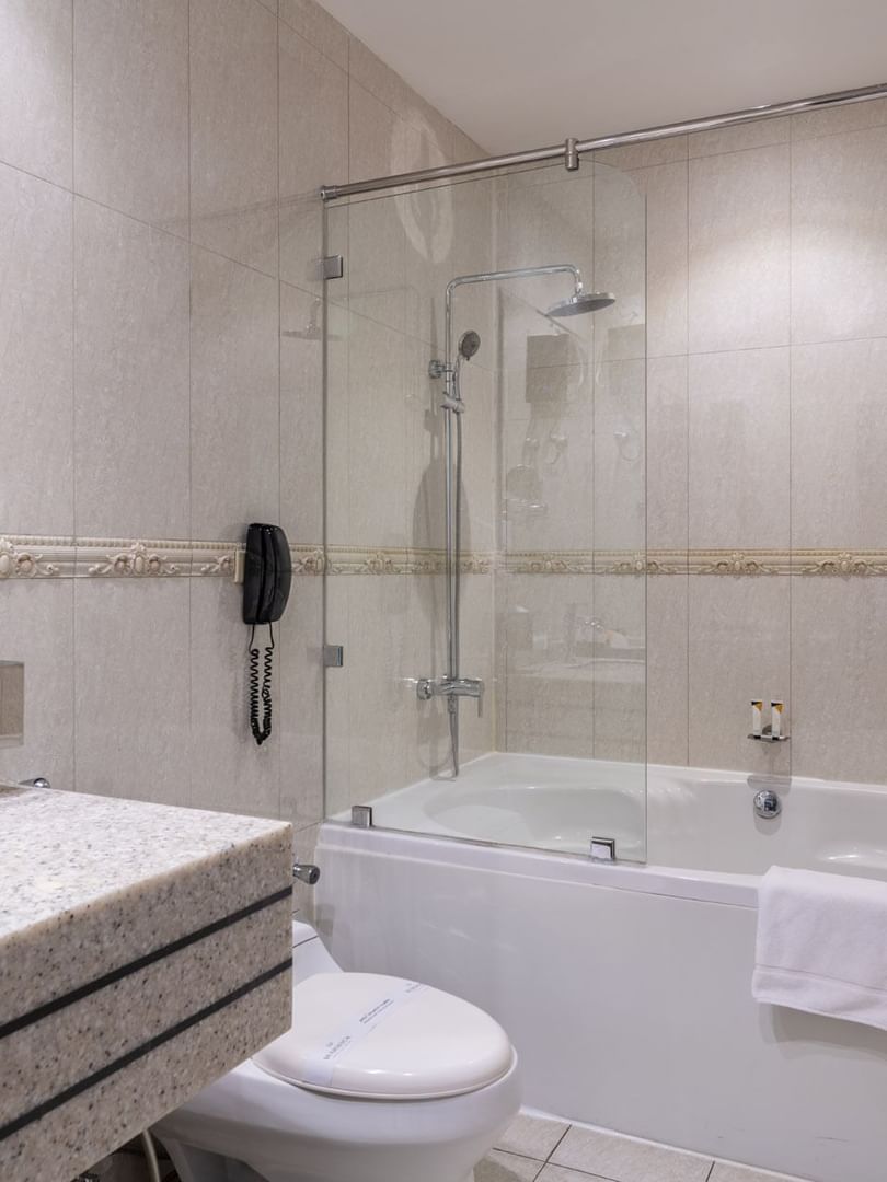 Executive Room Sea View features White bathtub with a glass screen by a granite sink & toilet at Warwick Al Jubail