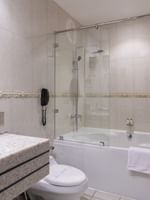 Executive Room Sea View features White bathtub with a glass screen by a granite sink & toilet at Warwick Al Jubail