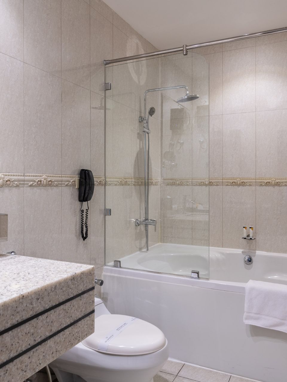 Executive Room Sea View features White bathtub with a glass screen by a granite sink & toilet at Warwick Al Jubail