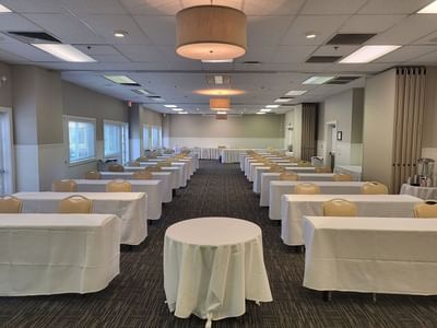 Classroom-style set up with white-draped tables, chairs, and modern lighting fixtures in Sutter Room at Lake Natoma Inn