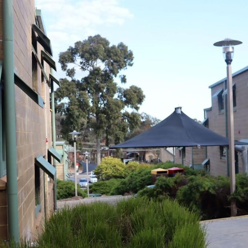 Green building exterior with a black canopy and greenery at La Trobe University.