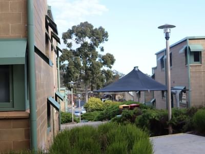 Green building exterior with a black canopy and greenery at La Trobe University.