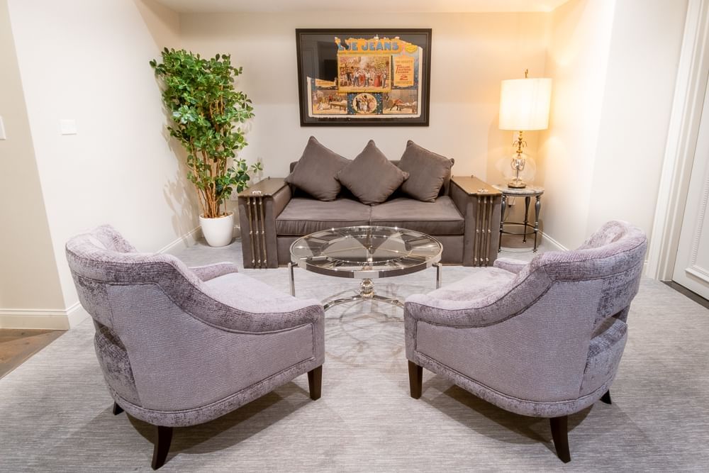 A seating area with a couch, two chairs, a coffee table, and a plant in a hotel suite.