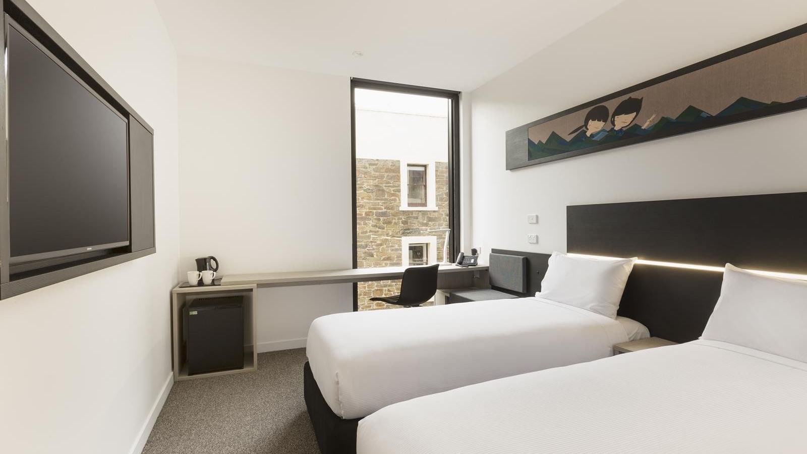 TV facing beds and workspace by the large window in Standard Room Two Single Beds at Ibis Adelaide
