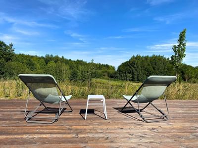 Two lounge chairs with a small table between them, overlooking a landscape of trees at the Avaneo Hotel Marktredwitz