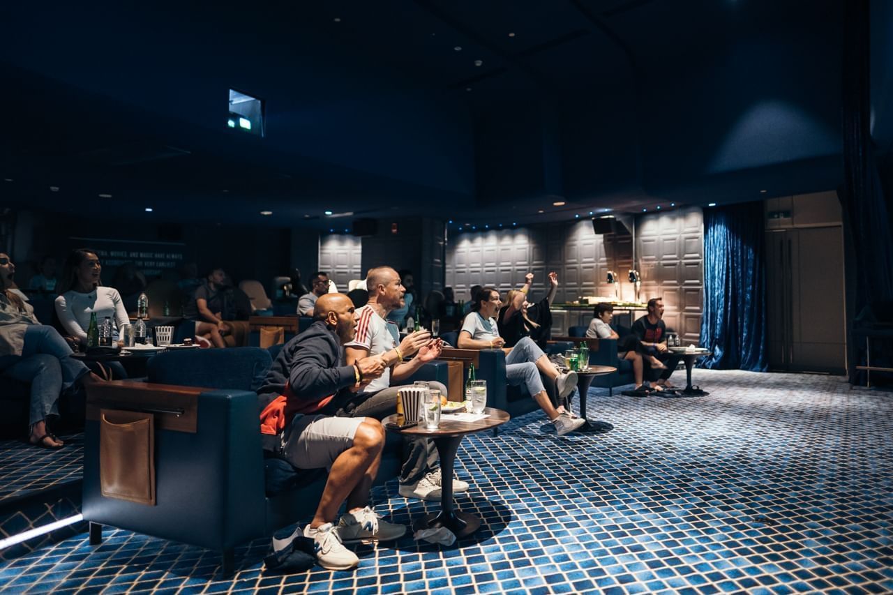 Guests watching a movie in the Private Dine-in Cinema with comfortable seating at Paramount Hotel Dubai