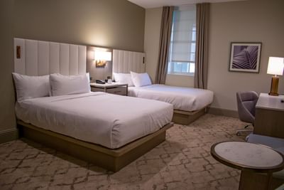 Standard Double Queen Grand with two queen beds featuring padded headboards and nightstands at Centennial Plaza Resort